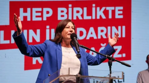 İncirli konuşurken kalabalığa bakıyor; arka planda pankartlar ve destekçiler bulunuyor