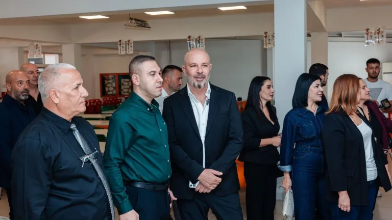 Bozkurt konuşurken ciddi bir ifade sergiliyor, arka planda belirsiz bir mekan görünümü